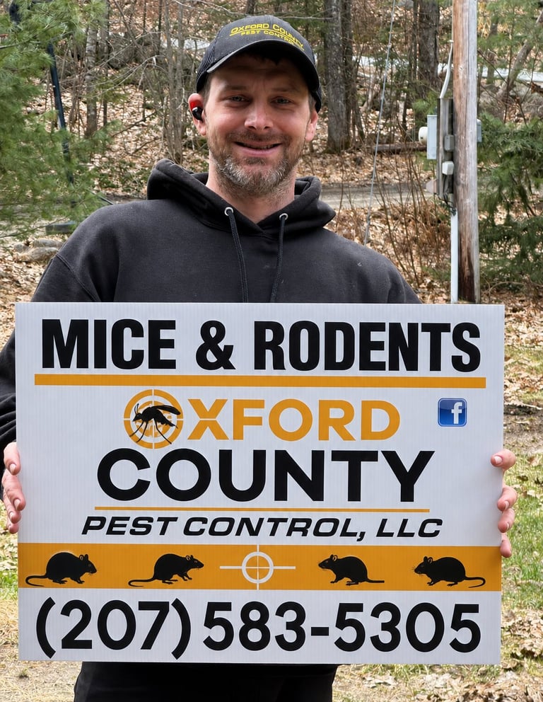 Man holding Oxford County Pest Control sign for mice and rodents removal service with phone number